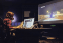 Paola Magrans trabajando en un moderno estudio de sonido frente a una pantalla de televisión gigante.